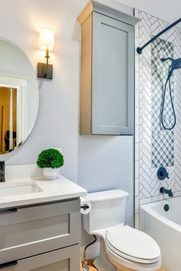 Elegant modern bathroom featuring chevron tiles, oval mirror, and sleek fixtures for a contemporary look.