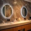 Elegant bathroom interior featuring a double vanity with circular backlit mirrors, sleek design.