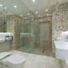 A sleek and spacious modern bathroom featuring elegant mosaic tiles and a glass shower.
