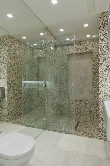 A sleek and spacious modern bathroom featuring elegant mosaic tiles and a glass shower.