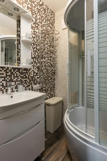 Stylish bathroom featuring mosaic tiles, round shower, and modern fixtures.
