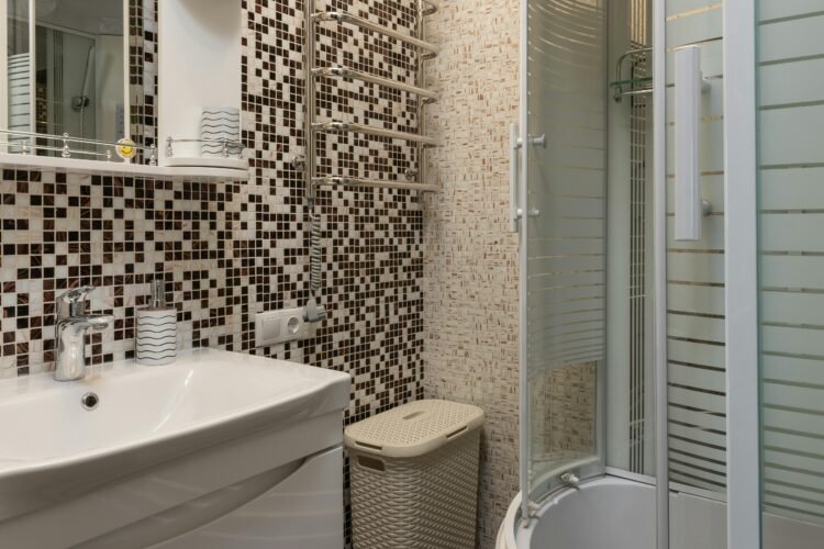 Stylish bathroom featuring mosaic tiles, round shower, and modern fixtures.