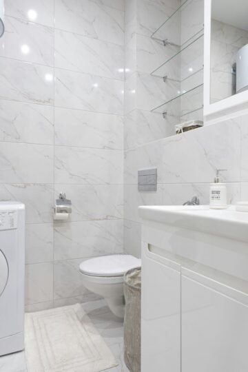 Bright minimalist bathroom featuring a washing machine and modern fixtures.