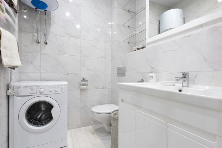 Bright minimalist bathroom featuring a washing machine and modern fixtures.