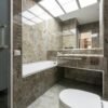Sleek marble-tiled bathroom with modern fixtures and ample lighting.
