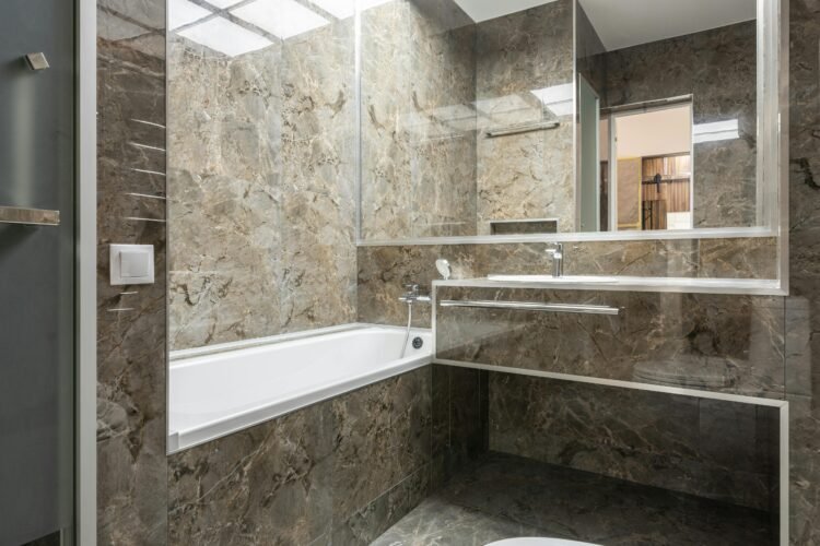 Sleek marble-tiled bathroom with modern fixtures and ample lighting.